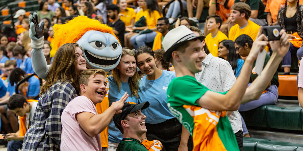 Students pose for a group selfie with Temoc at convocation.